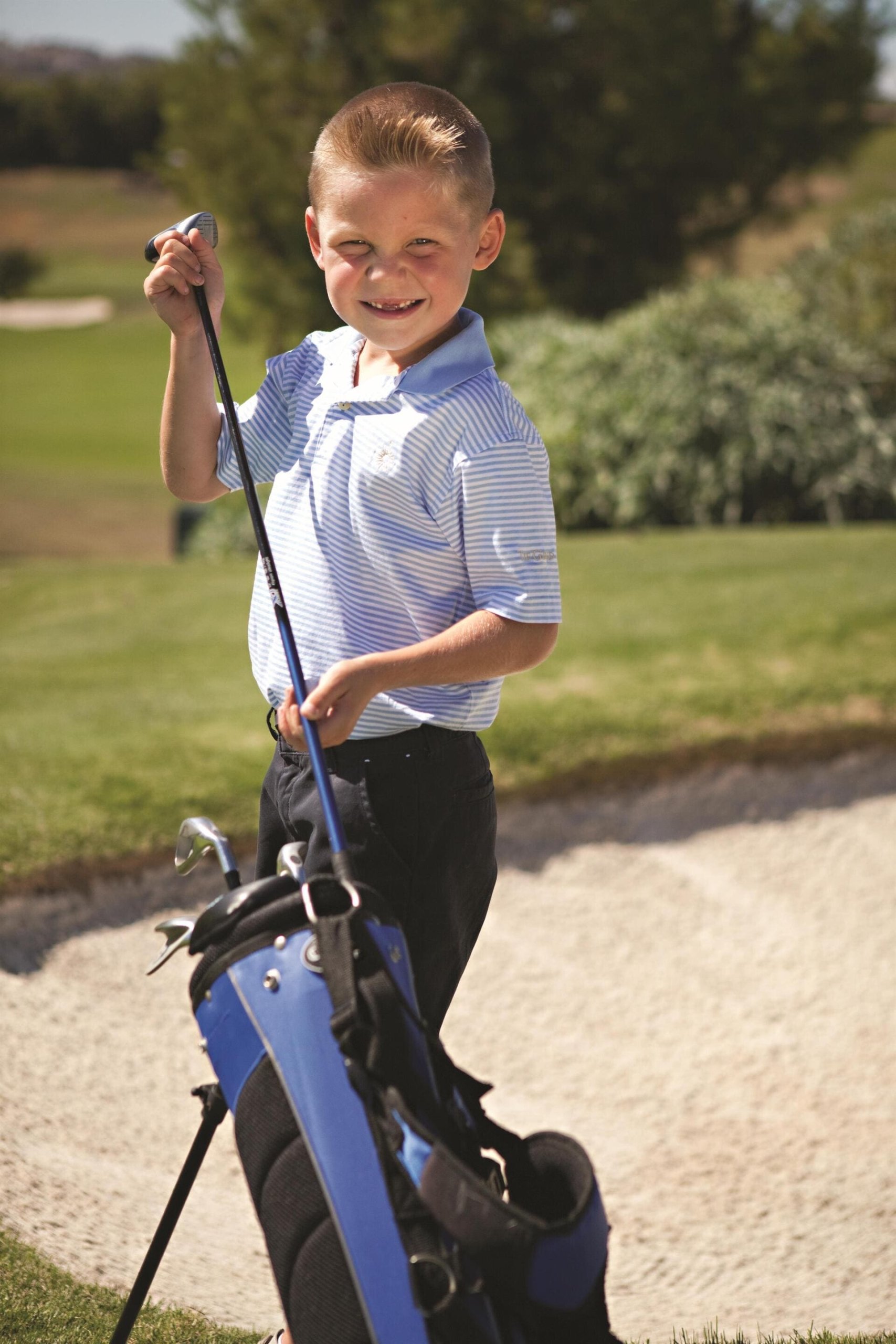 A kid taking a club out of his caddy bag