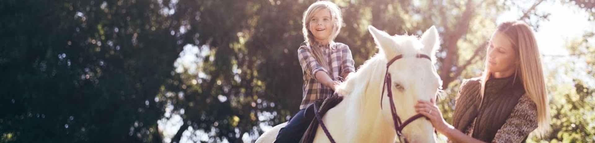a mother guiding her son on a pony